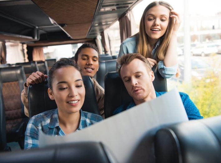 young-happy-tourists-looking-at-map-during-trip-on-travel-bus.jpg